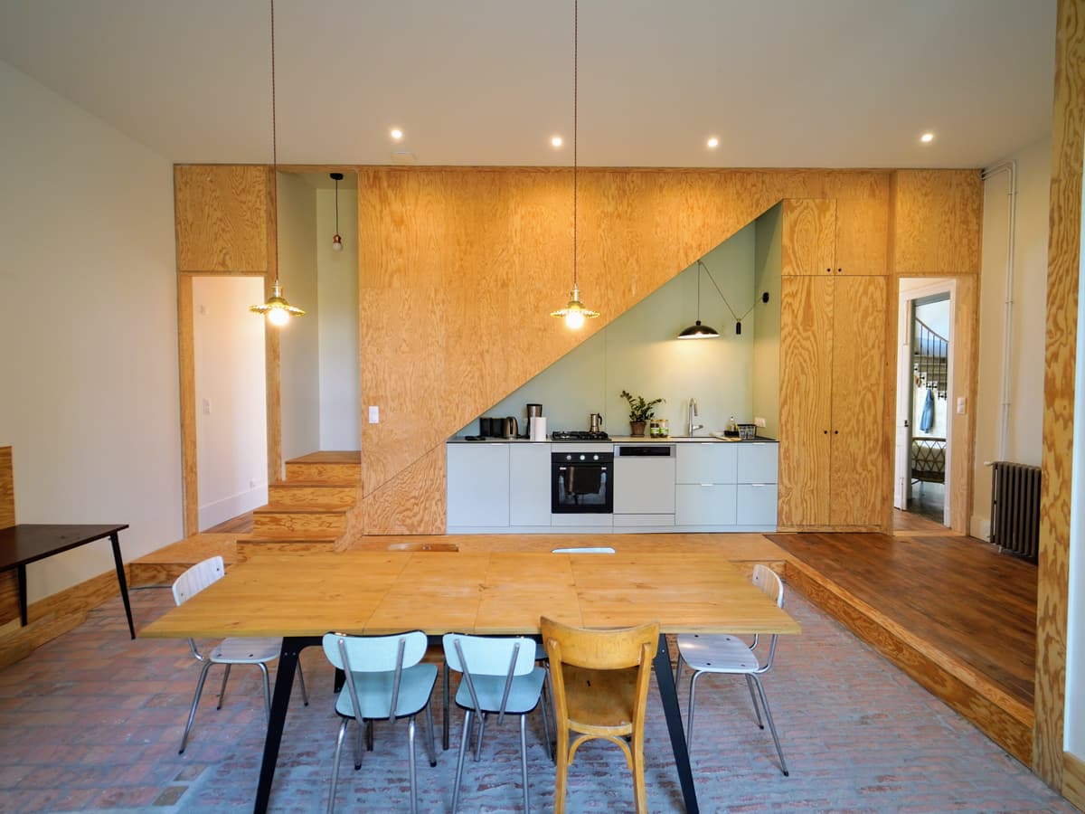 La cuisine et sa grande table sous l'escalier en bois clair